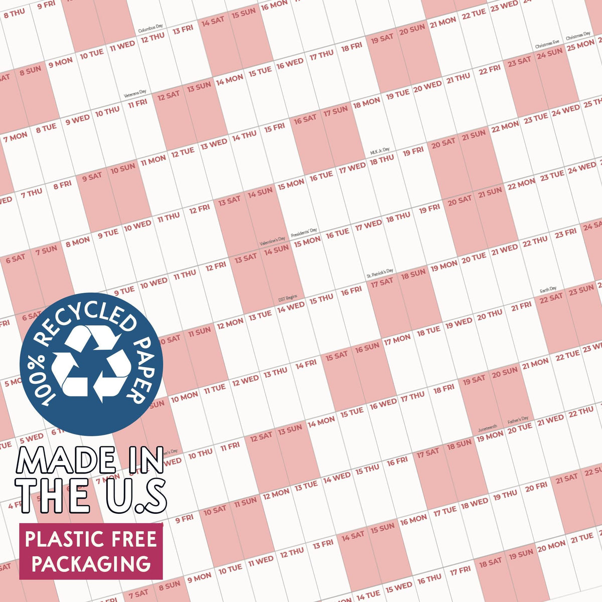 May include: A wall calendar featuring a grid layout with alternating white and light pink columns. Each cell contains a day number and a three-letter abbreviation for the day of the week. A blue circular badge states 100% RECYCLED PAPER, MADE IN THE U.S, and PLASTIC FREE PACKAGING.