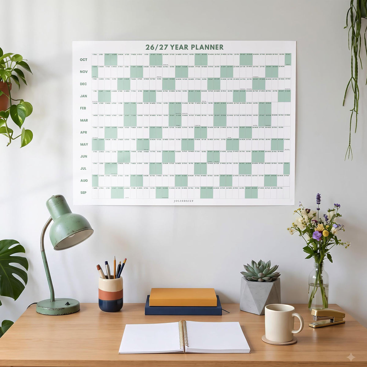 May include: A wall-mounted 26/27 year planner featuring a grid layout with alternating white and sage green blocks. The calendar displays months from October to September with clear text headers and a grid structure for daily tracking and organization.