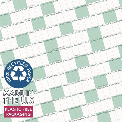 May include: A wall calendar featuring a grid of days with alternating white and light green columns. A circular blue badge displays the text 100% RECYCLED PAPER, MADE IN THE U.S, and PLASTIC FREE PACKAGING in white and black lettering.