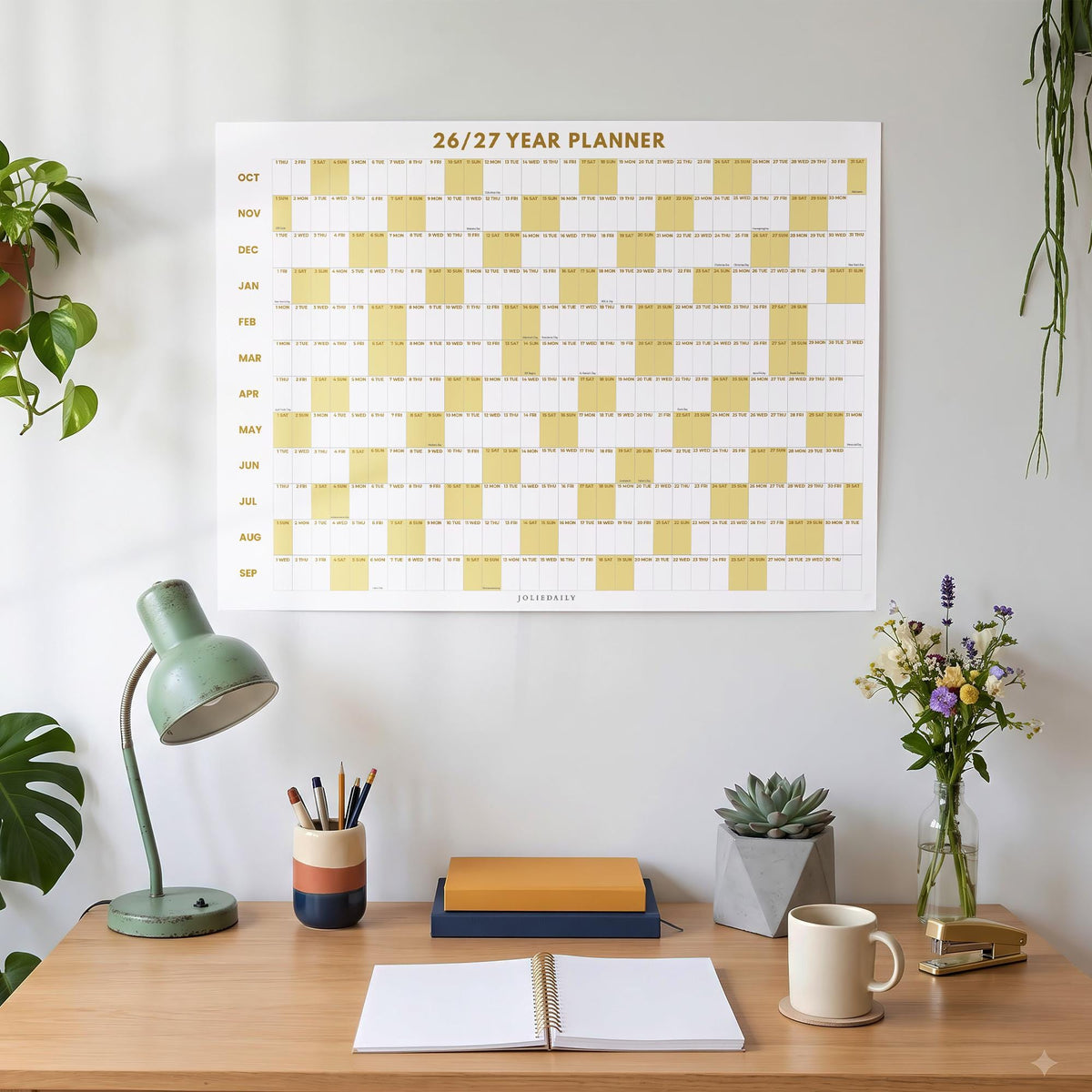May include: A wall-mounted 26/27 year planner featuring a grid layout with alternating white and mustard yellow blocks. The calendar displays months from October to September with clear text headings and a clean, organized design for tracking dates.