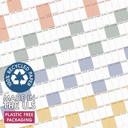 May include: A wall calendar featuring a grid layout with alternating colored blocks in peach, gray, blue, and yellow. A circular blue badge displays the text 100% RECYCLED PAPER, MADE IN THE U.S, and PLASTIC FREE PACKAGING over the calendar grid.