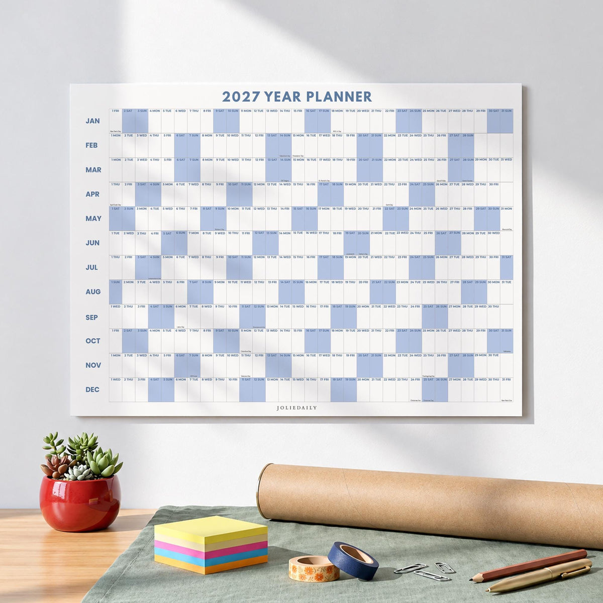 May include: A 2027 year planner wall calendar featuring a grid layout with months listed vertically from January to December. The design includes alternating light blue and white rectangular blocks for days, with the text 2027 YEAR PLANNER at the top.