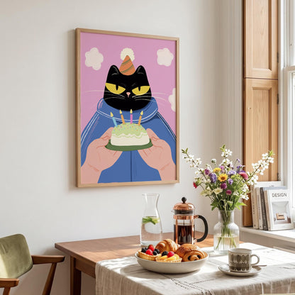 May include: A framed art print featuring a black cat wearing a party hat and holding a birthday cake with lit candles. The cat is set against a pink background with white cloud shapes. The artwork is in a wooden frame.