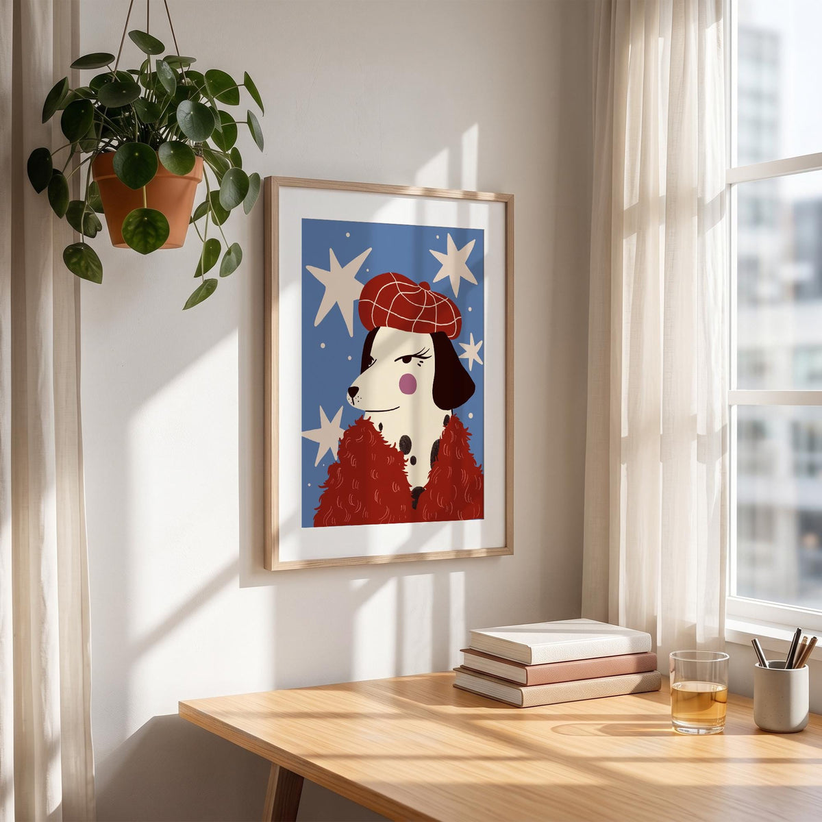 May include: A framed art print featuring a Dalmatian dog wearing a red beret and a red fluffy scarf against a blue background with white star shapes. The artwork is displayed on a wall above a wooden desk.