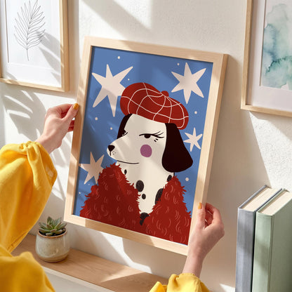 May include: A framed art print featuring a Dalmatian dog wearing a red beret and a red fluffy scarf against a blue background with white star shapes. The dog has black spots and a pink cheek. The frame is made of light-colored wood.