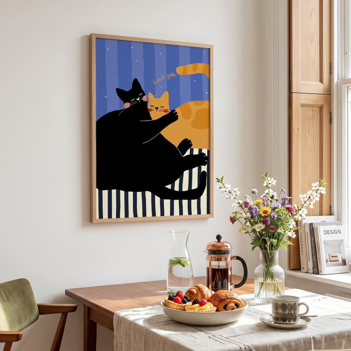 May include: A framed art print featuring two cartoon cats. One black cat hugs an orange cat against a blue striped background. The words "Loves you" are written above the cats. The print is in a wooden frame.