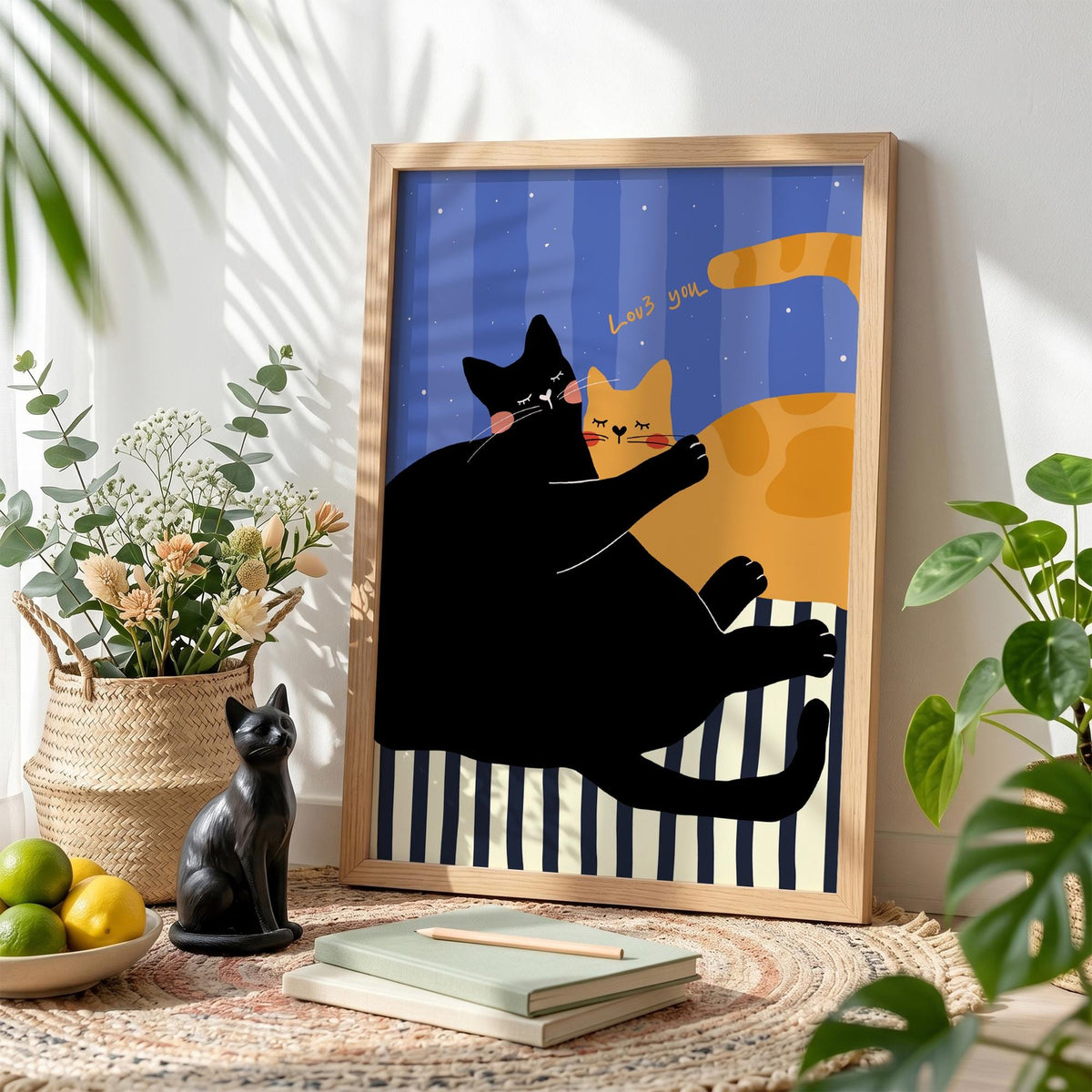 May include: A framed art print featuring a black cat embracing an orange cat. The background has blue stripes and the words "Love you". The print is in a wooden frame and is displayed on a rug.