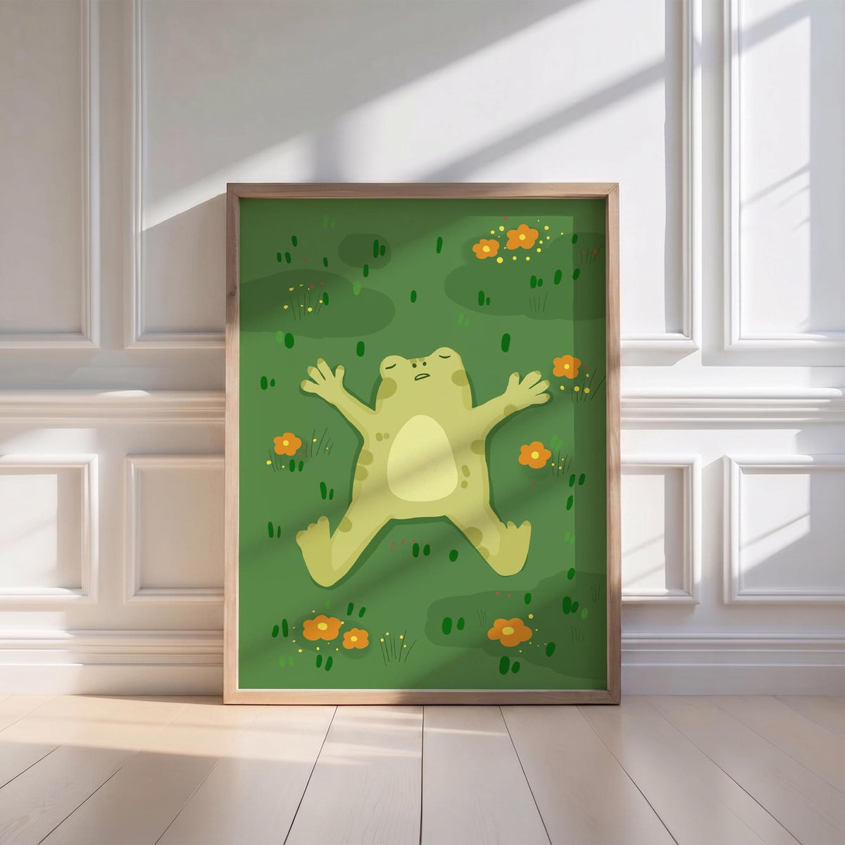 May include: A framed art print featuring a cartoon frog lying on its back in a field of green grass and orange flowers. The frog is light green with a cream-colored belly. The artwork is in a wooden frame.