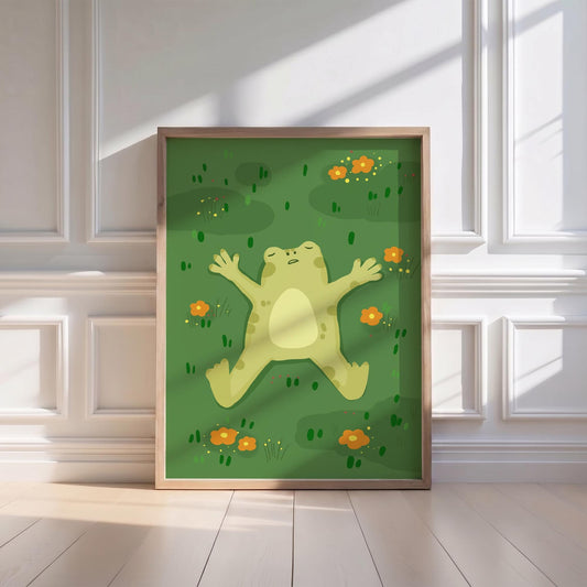 May include: A framed art print featuring a cartoon frog lying on its back in a field of green grass and orange flowers. The frog is light green with a cream-colored belly. The artwork is in a wooden frame.