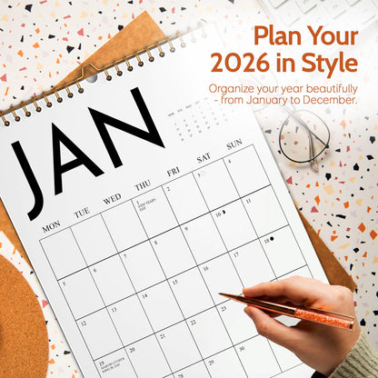 May include: A large, open calendar for January 2026, with the word "JAN" in bold black letters. The calendar is open to the first month, with a pen poised over a date. The text "Plan Your 2026 in Style" is displayed at the top.