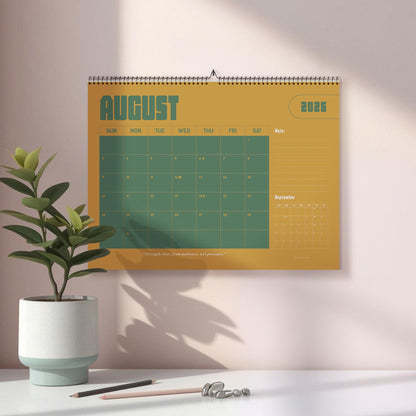 May include: A wall calendar for August 2026, featuring a mustard yellow background with green grid lines and text. The word "AUGUST" is prominently displayed. A small plant in a white and blue pot sits on a white surface.