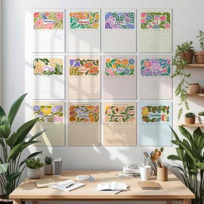 May include: A collection of twelve floral-themed wall calendars, each representing a month of the year. The calendars feature colorful illustrations of flowers and foliage, with the month's name displayed at the top. The calendars are arranged on a white wall above a wooden desk.