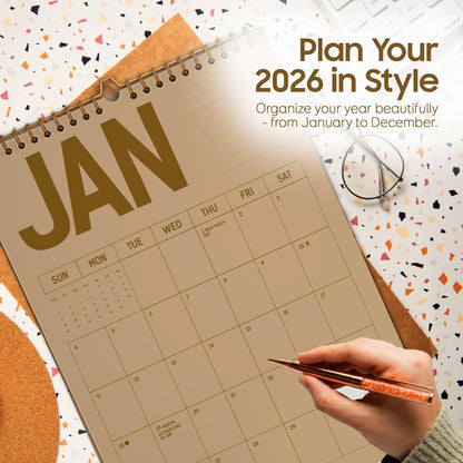 May include: A spiral-bound 2026 calendar open to January, with the word "JAN" in large, gold letters. The calendar is on a patterned surface with the text "Plan Your 2026 in Style" and "Organize your year beautifully - from January to December."