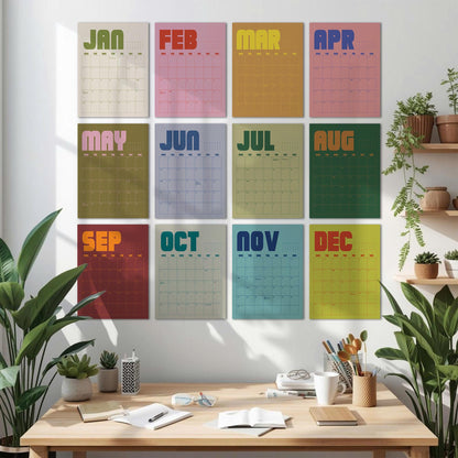 May include: A set of twelve colorful monthly calendars displayed on a white wall. Each calendar features a different color background with the month's name in bold, retro-style lettering. The calendars are arranged in a grid pattern.