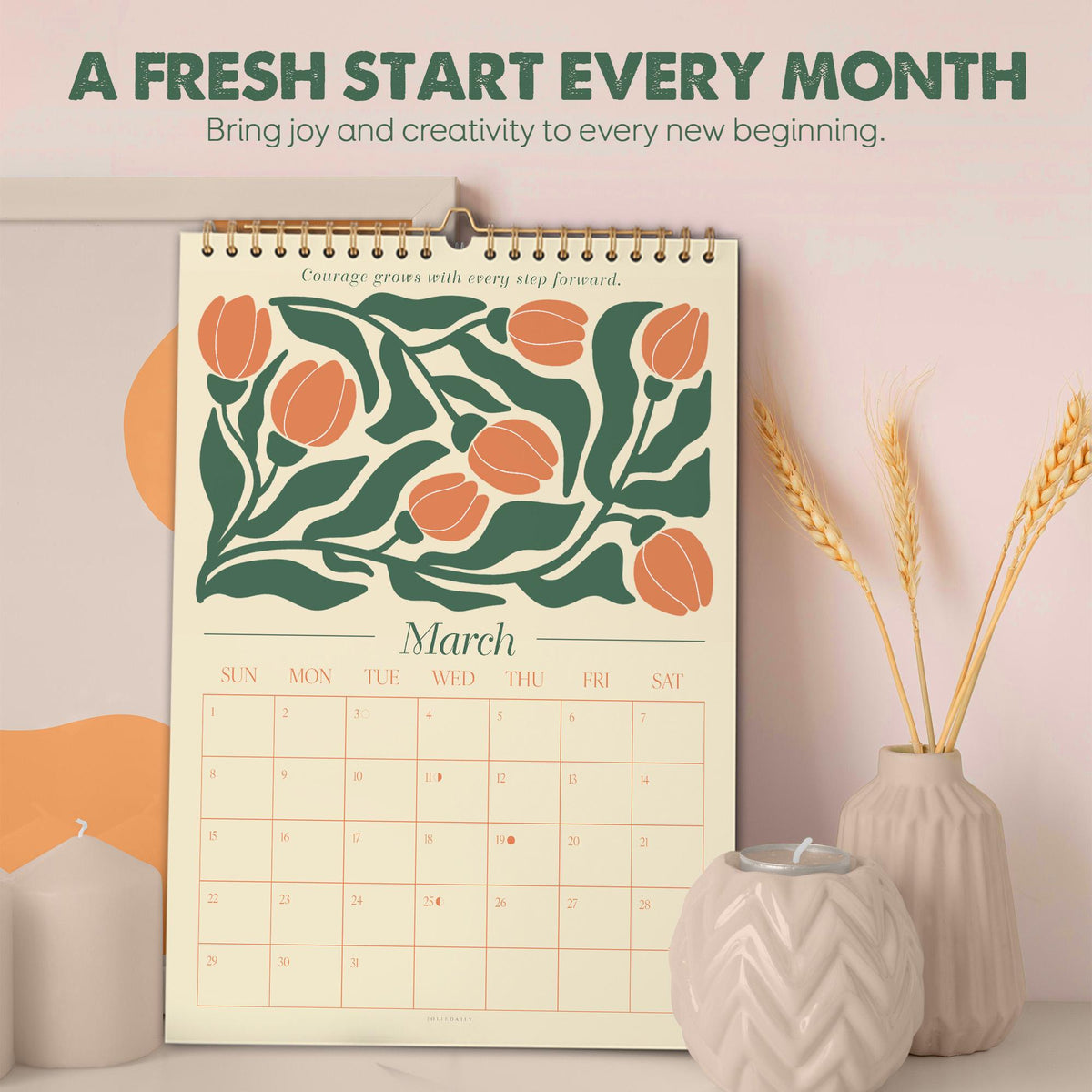 May include: A spiral-bound wall calendar for March with a floral design in orange and green. The calendar has the text "A Fresh Start Every Month" and "Bring joy and creativity to every new beginning." The calendar is displayed with decorative vases and candles.