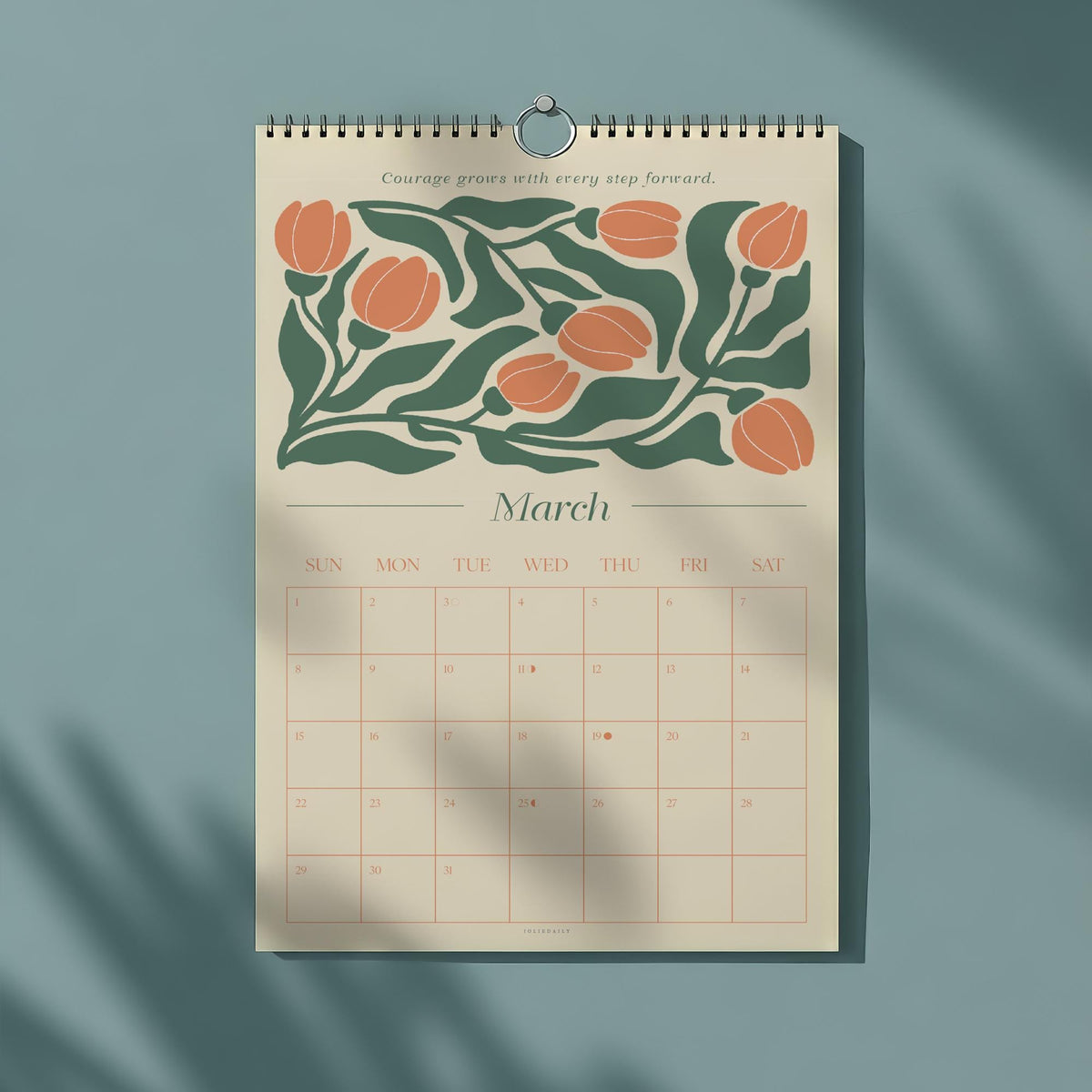 May include: A spiral-bound wall calendar for March, featuring a floral design with orange blooms and green leaves. The calendar has a beige background with a grid of dates and the text "Courage grows with every step forward."