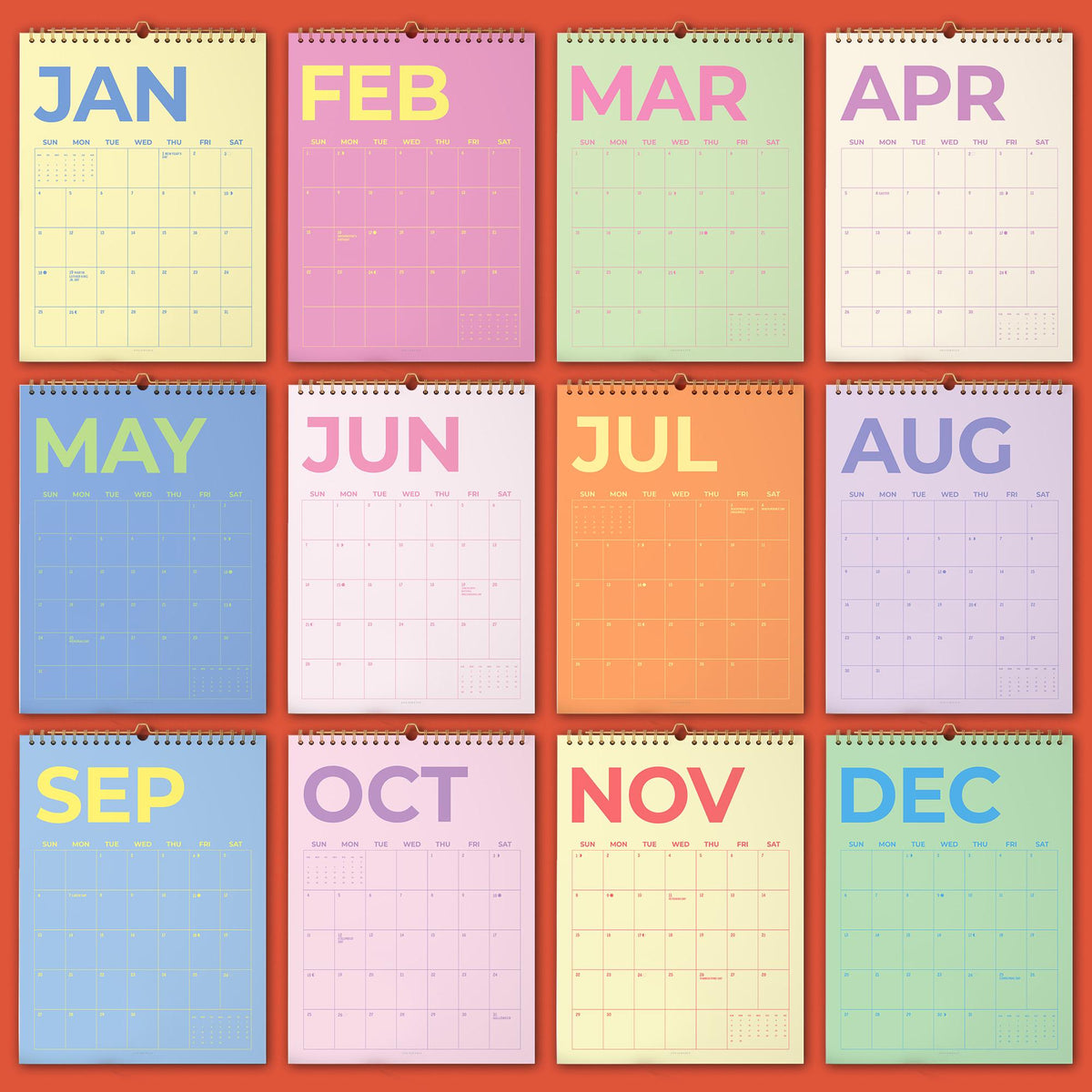 May include: A collection of twelve colorful monthly wall calendars. Each calendar features a different month's name in bold letters, with a corresponding color scheme. The calendars are arranged in a grid, showcasing the full year.