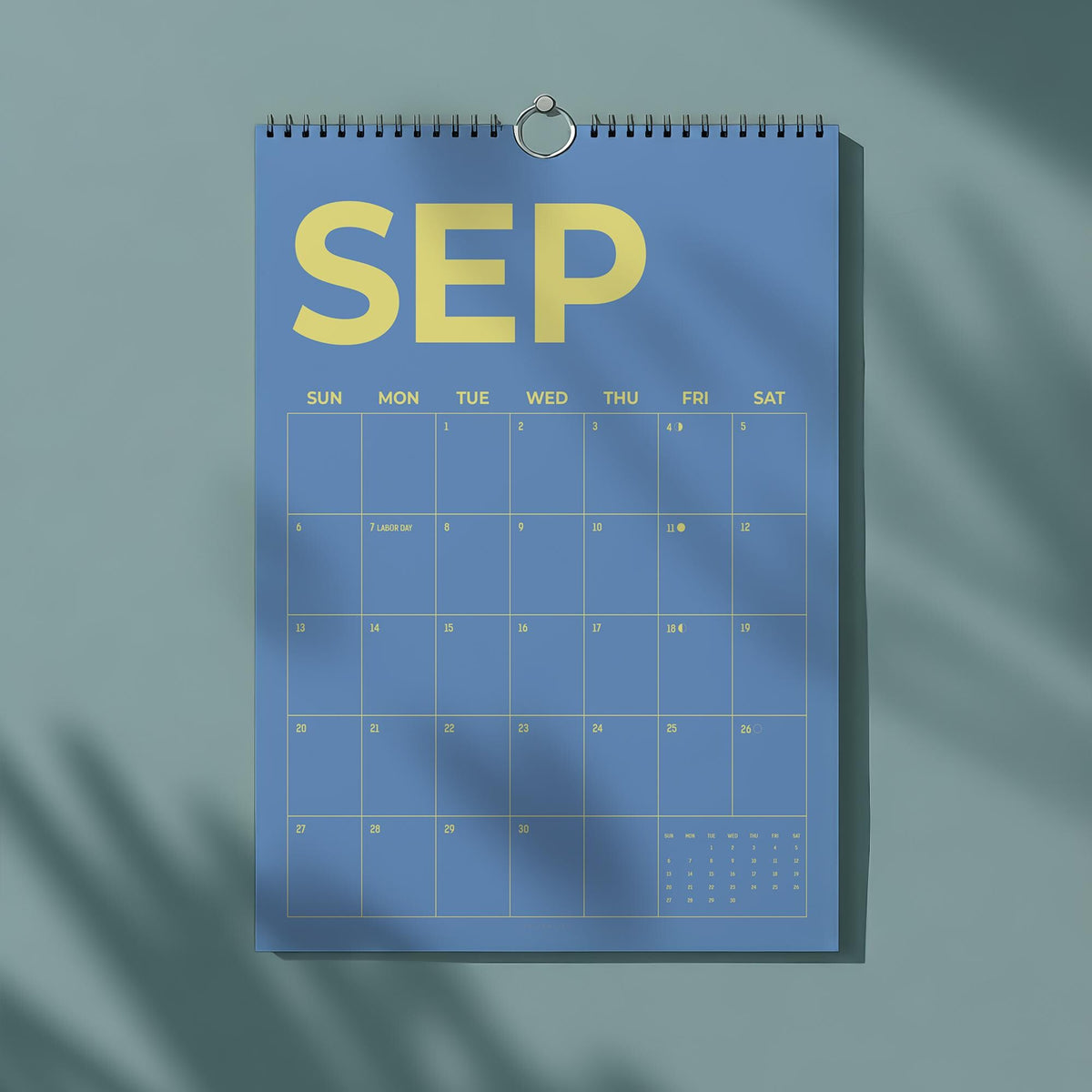 May include: A blue wall calendar for September with yellow text. The word "SEP" is at the top, with the days of the week and dates below. The calendar is hanging from a silver ring.