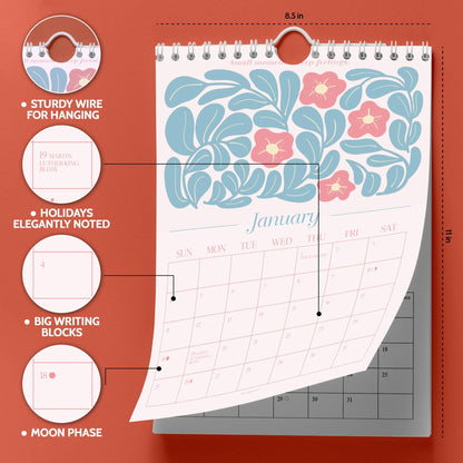 May include: A wall calendar with a floral design in blue and pink. The calendar is 8.5 inches wide and 11 inches tall. Features include sturdy wire for hanging, holidays elegantly noted, big writing blocks, and moon phase indicators.