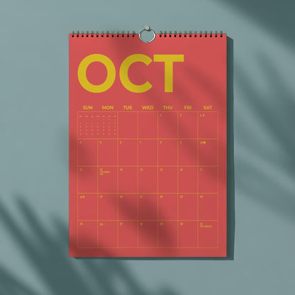 May include: A red wall calendar for October with yellow text. The word "OCT" is prominently displayed at the top. The calendar grid is visible, with dates and days of the week. A metal ring holds the calendar.