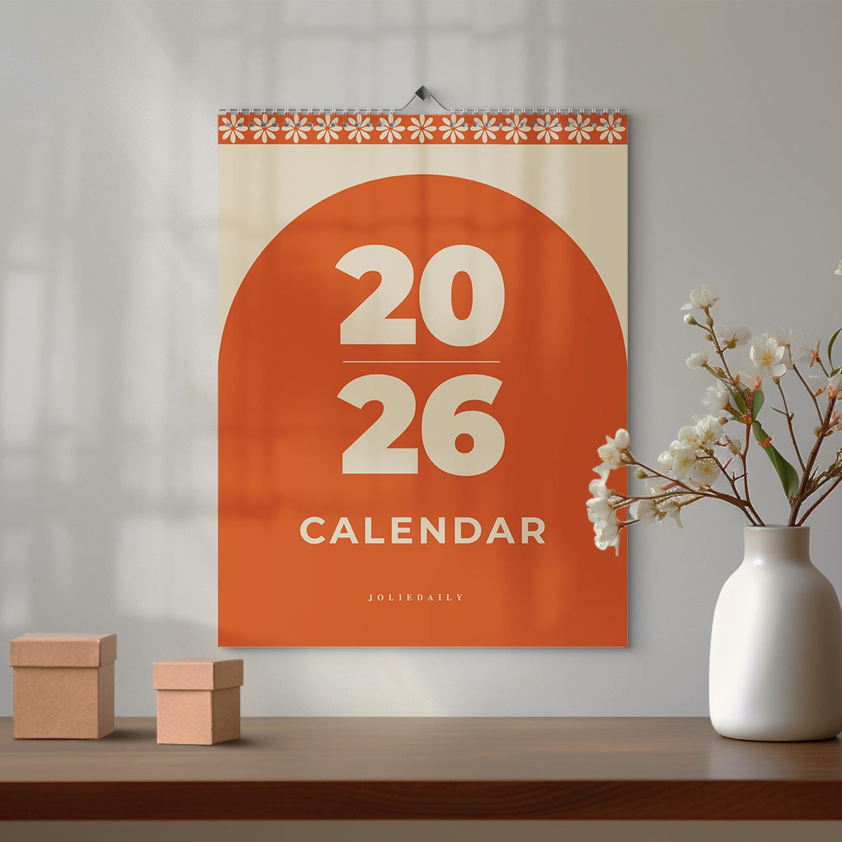 May include: A 2026 calendar with a large orange semi-circle design. The calendar has the numbers "20" and "26" in a bold, off-white font, with the word "CALENDAR" below. The top border features a daisy pattern.