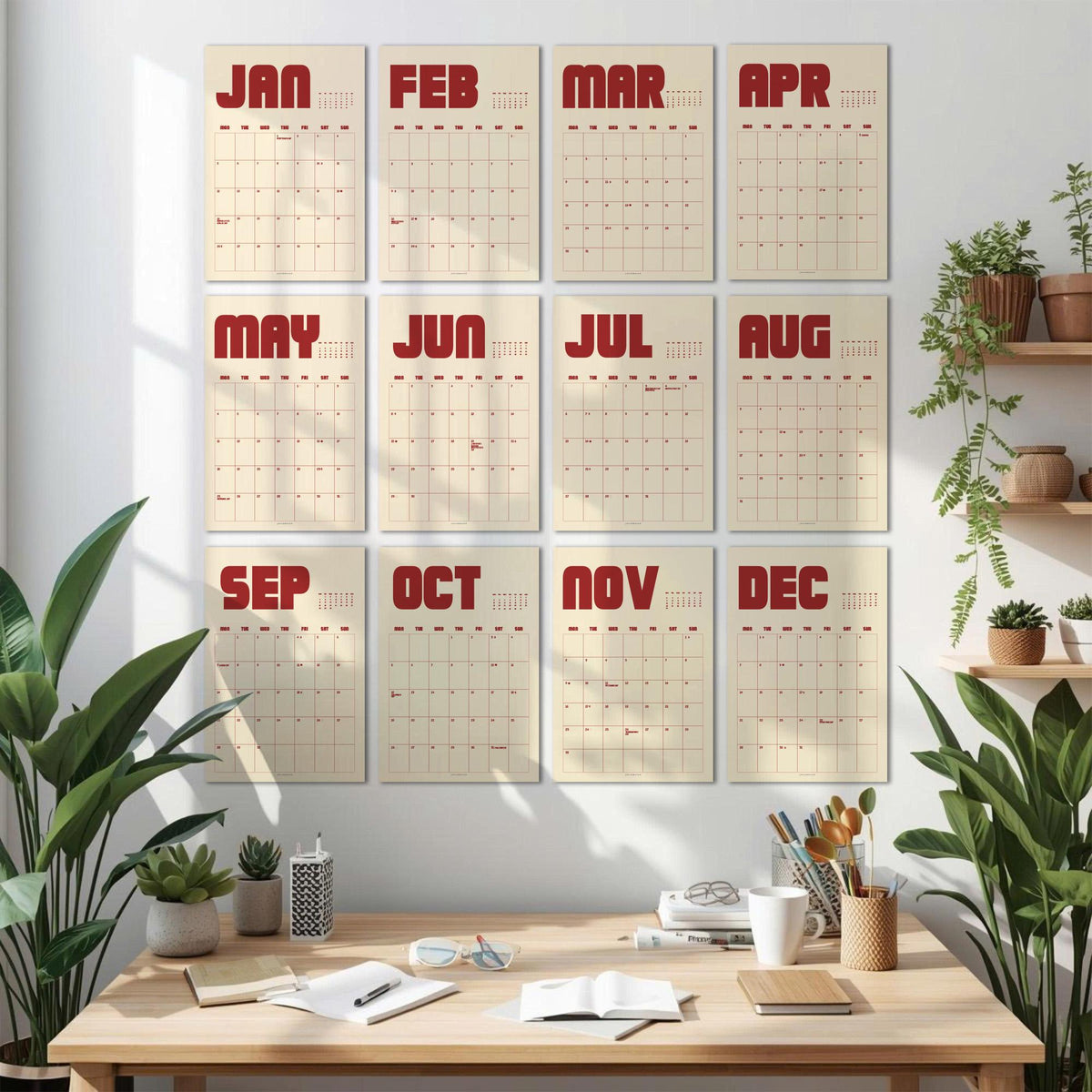 May include: A set of twelve monthly calendars displayed on a white wall. Each calendar features a cream-colored background with a grid of dates and a bold, red month name at the top. The calendars are arranged in three rows of four.
