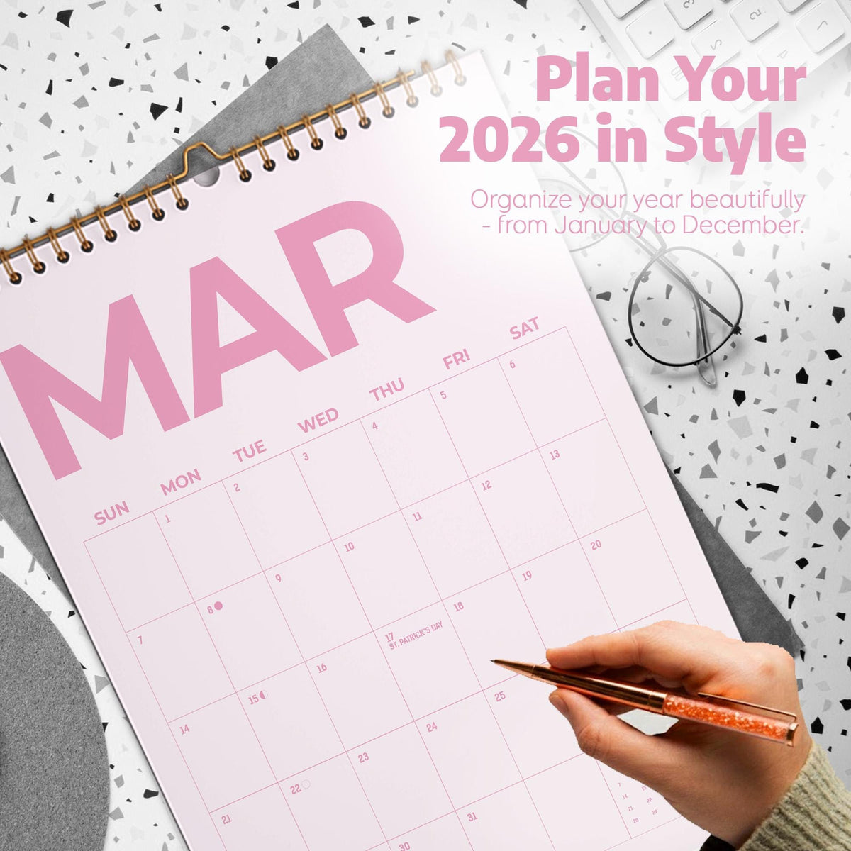 May include: A 2026 wall calendar with a spiral binding, featuring the month of March in large pink letters. The calendar includes a grid for dates, the text Plan Your 2026 in Style, and Organize your year beautifully - from January to December.