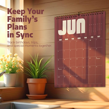 May include: A wall calendar for the month of June featuring a dark red and brown striped design with white text that reads Keep Your Family's Plans in Sync and Track birthdays, trips, and special moments together. The calendar has a wire binding.