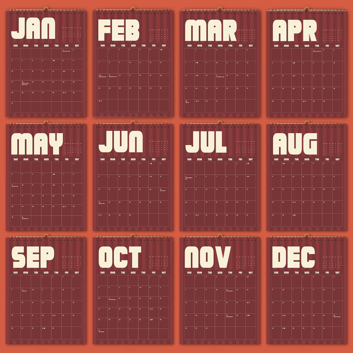 May include: A twelve-month wall calendar featuring a deep maroon background with vertical stripes. Each month is displayed in a separate grid with bold, cream-colored sans-serif lettering for the months JAN through DEC and days of the week.