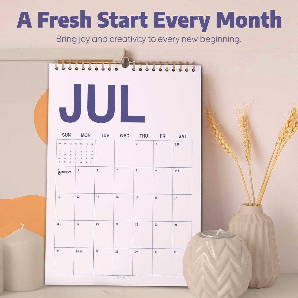 May include: A wall calendar for the month of July with a white background, dark blue text, and a gold spiral binding. The text reads A Fresh Start Every Month, Bring joy and creativity to every new beginning, and JUL. The grid shows days of the week.