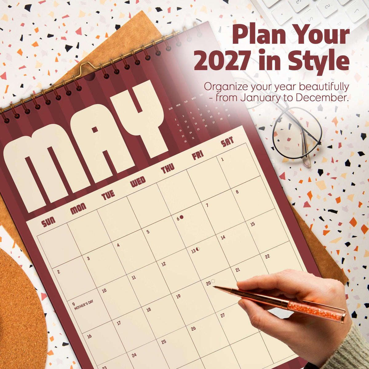 May include: A 2027 wall calendar featuring a maroon and cream color scheme with the month of May displayed. The text reads Plan Your 2027 in Style, Organize your year beautifully - from January to December, and Mother's Day on the 9th.