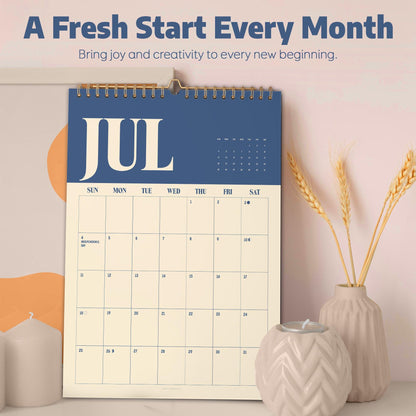 May include: A wall calendar featuring the month of July with a dark blue header and cream-colored grid. The text reads A Fresh Start Every Month, Bring joy and creativity to every new beginning, and JUL. It includes a grid for dates.