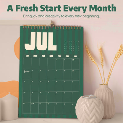 May include: A wall calendar with a dark green background and vertical stripes, displaying the month of July. The text reads A Fresh Start Every Month, Bring joy and creativity to every new beginning, and JUL. It features a grid for dates.