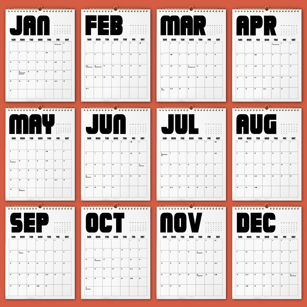 May include: A wall calendar featuring twelve white pages with black text for each month from January to December. Each page displays a grid for the days of the week, with bold, sans-serif month names at the top and a spiral binding at the center.