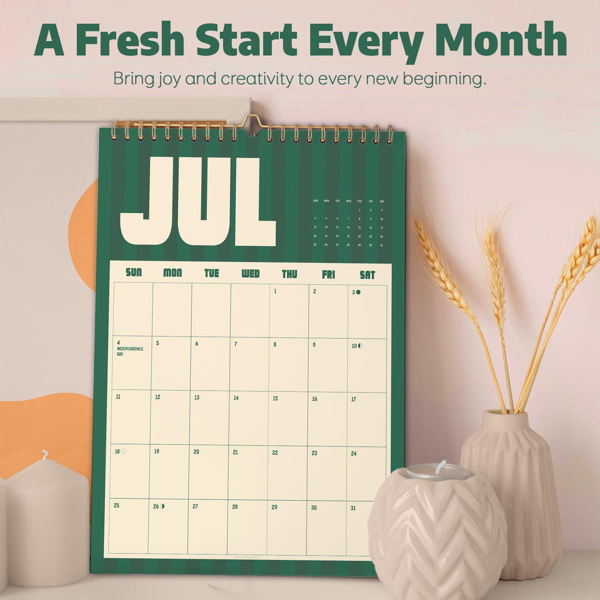 May include: A wall calendar featuring a dark green background with vertical stripes and the text JUL in large white letters. The grid displays days of the week and dates for July, with the text A Fresh Start Every Month and Bring joy and creativity to every new beginning printed above the calendar.