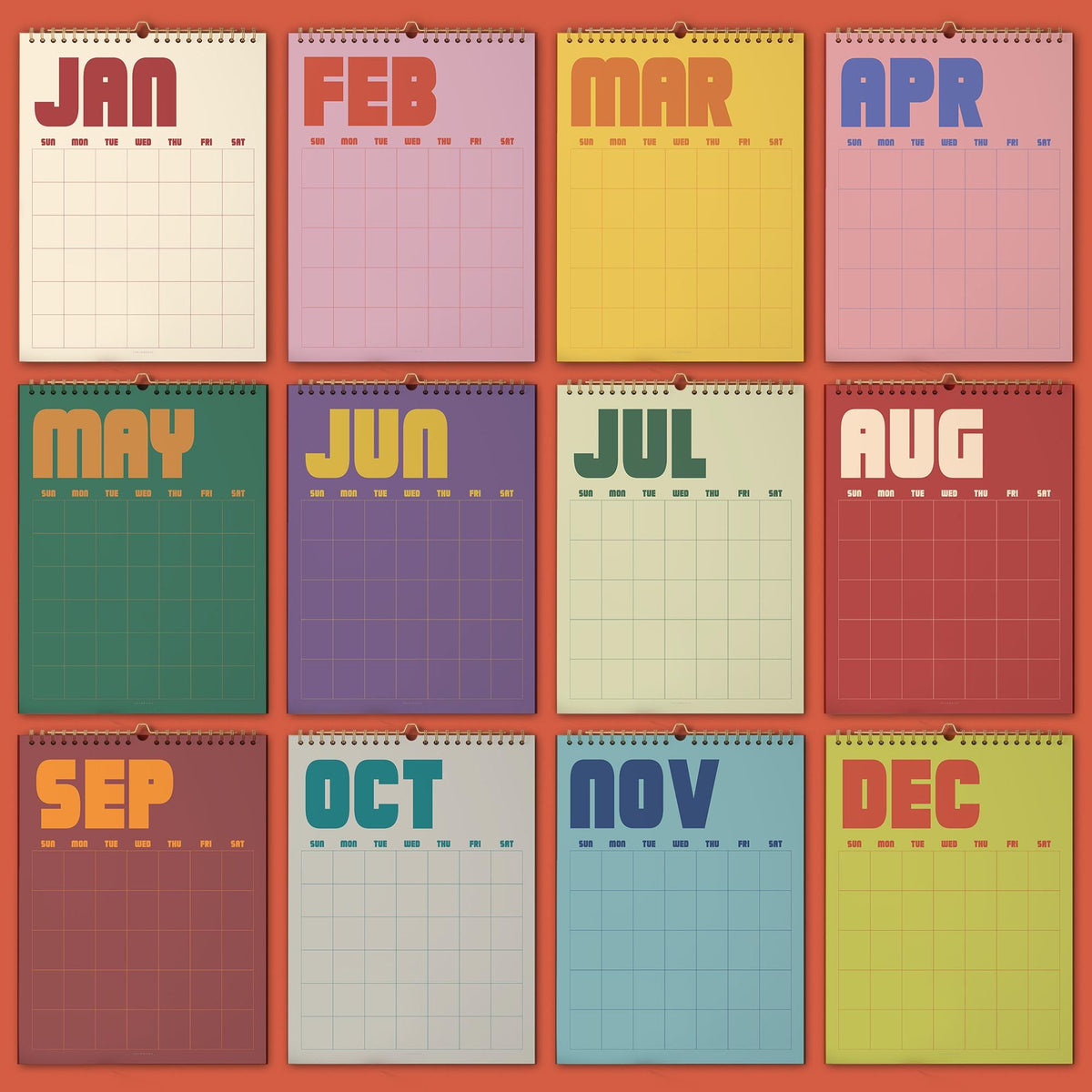 May include: A twelve-month wall calendar featuring a grid layout for each month. Each page displays the month name in large, bold, colorful typography at the top, followed by a grid with columns for days of the week from Sunday to Saturday.
