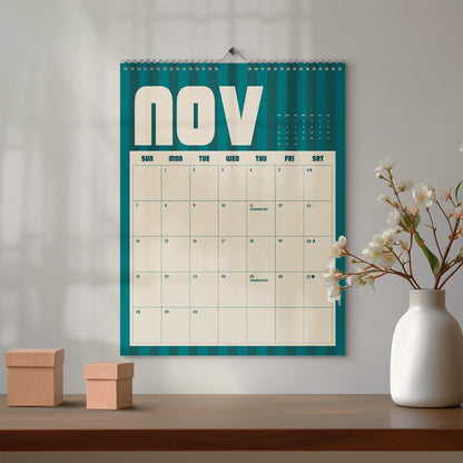 May include: A wall calendar for the month of November featuring a teal and dark teal vertical striped background. The calendar grid is cream-colored with black text, displaying the days of the week and dates, including Veterans Day and Thanksgiving.