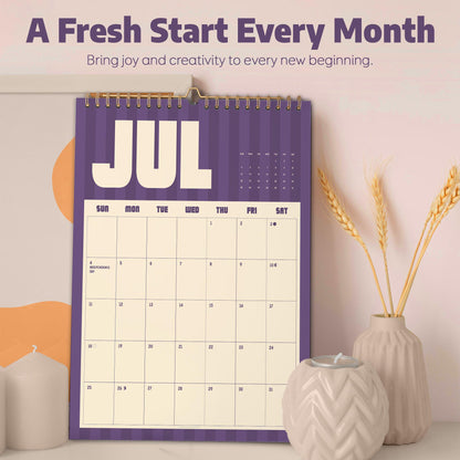 May include: A wall calendar featuring a purple and cream color scheme with the text A Fresh Start Every Month and Bring joy and creativity to every new beginning. The calendar page displays the month of July with a grid layout and spiral binding.