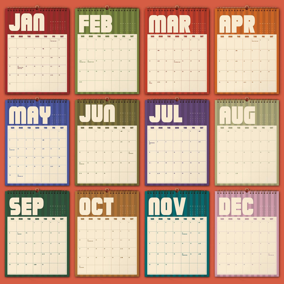 May include: A twelve-month wall calendar featuring a grid layout for each month from January to December. Each month is displayed on a separate page with a distinct color background, bold white lettering for the month name, and a cream-colored grid.