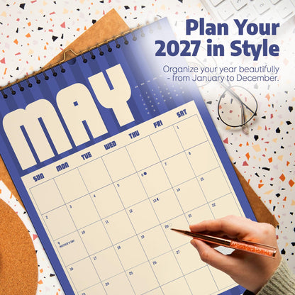 May include: A spiral-bound 2027 wall calendar featuring a blue and cream color scheme. The page displays the month of May with a grid of numbered days, including the text Plan Your 2027 in Style and Organize your year beautifully - from January to December.