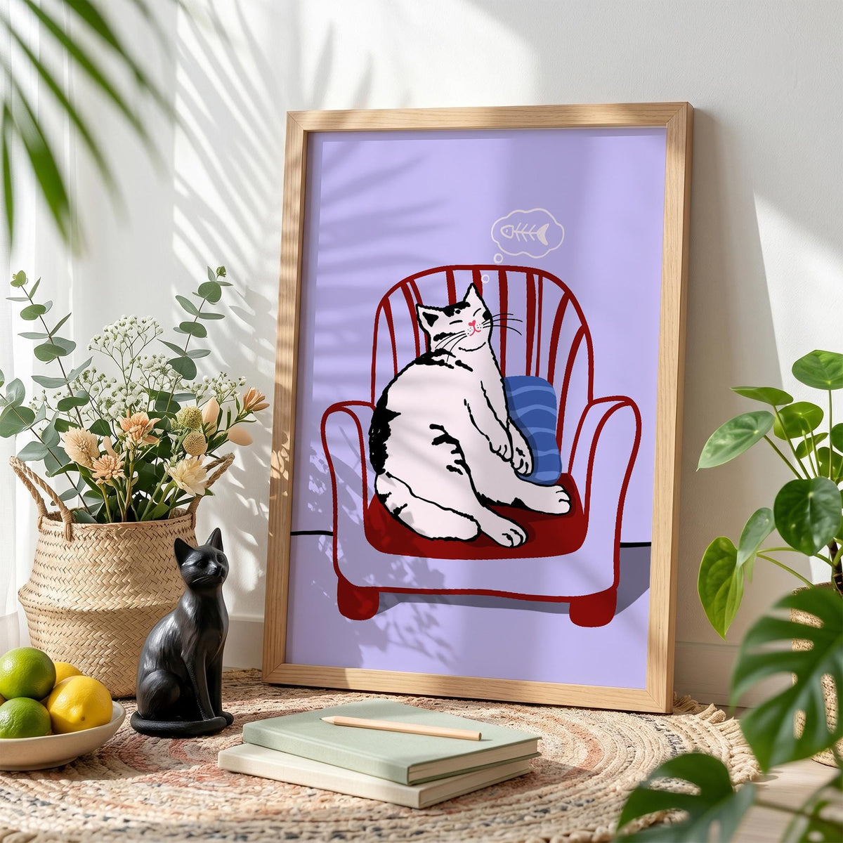 May include: A framed art print featuring a relaxed cat sitting in a red armchair with a blue pillow. The cat is white with black markings. A thought bubble with a fishbone is above the cat's head. The background is a light purple.