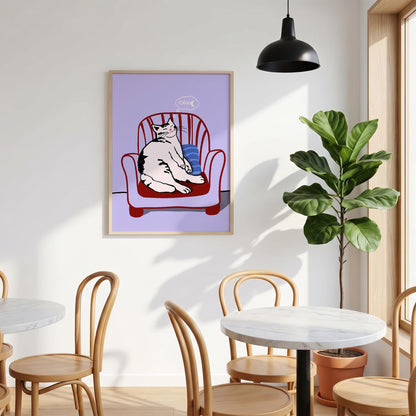 May include: A framed print featuring a cartoon cat lounging in a red armchair. The cat is white with black markings and is sitting on a blue pillow. A thought bubble above the cat shows a fish bone.