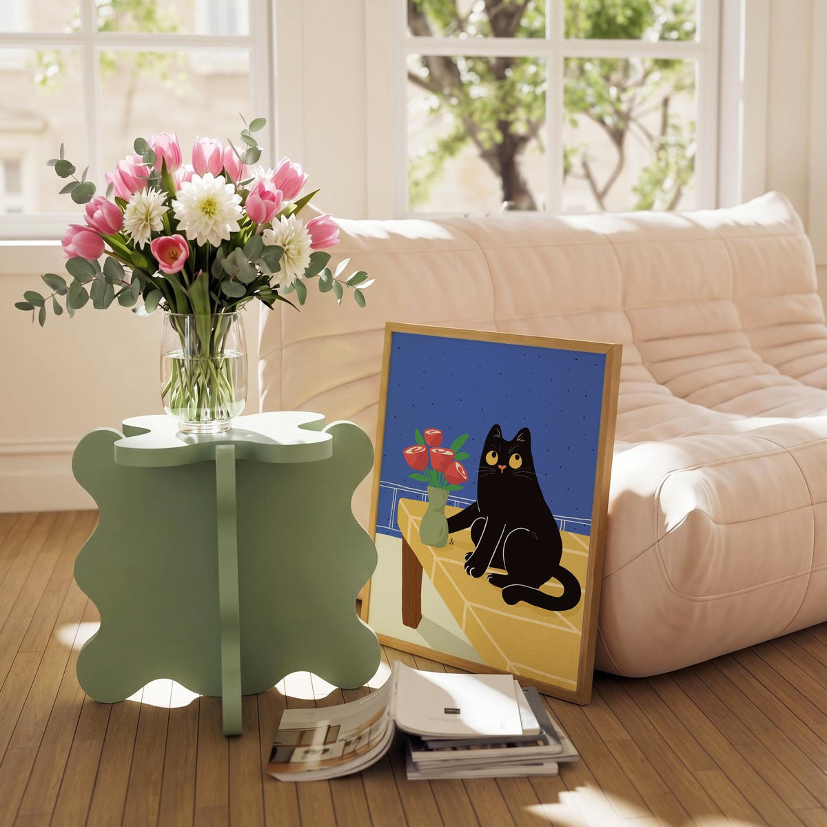 May include: A light green, four-leaf clover-shaped side table holds a clear glass vase filled with pink tulips, white dahlias, and eucalyptus. A framed art print of a black cat and a vase of red roses rests on the floor.